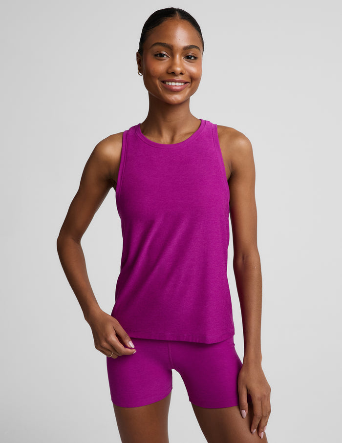 Woman wearing a purple lightweight classic length tank top and biker shorts against a plain background.