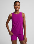 Woman wearing a purple lightweight classic length tank top and biker shorts against a plain background.