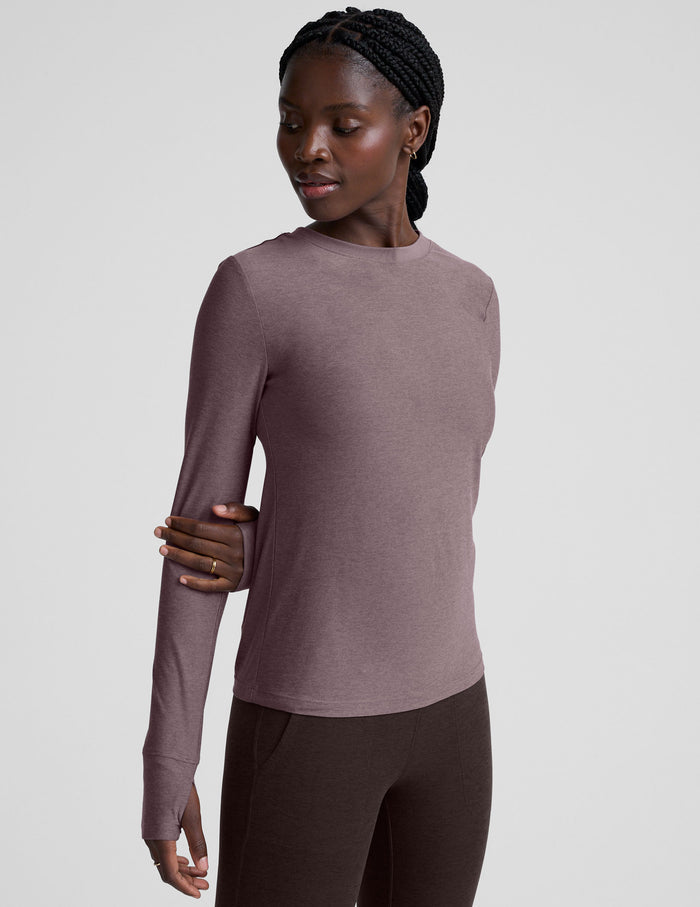 model wearing a mauve long-sleeve fitted crew neck top against a plain background.
