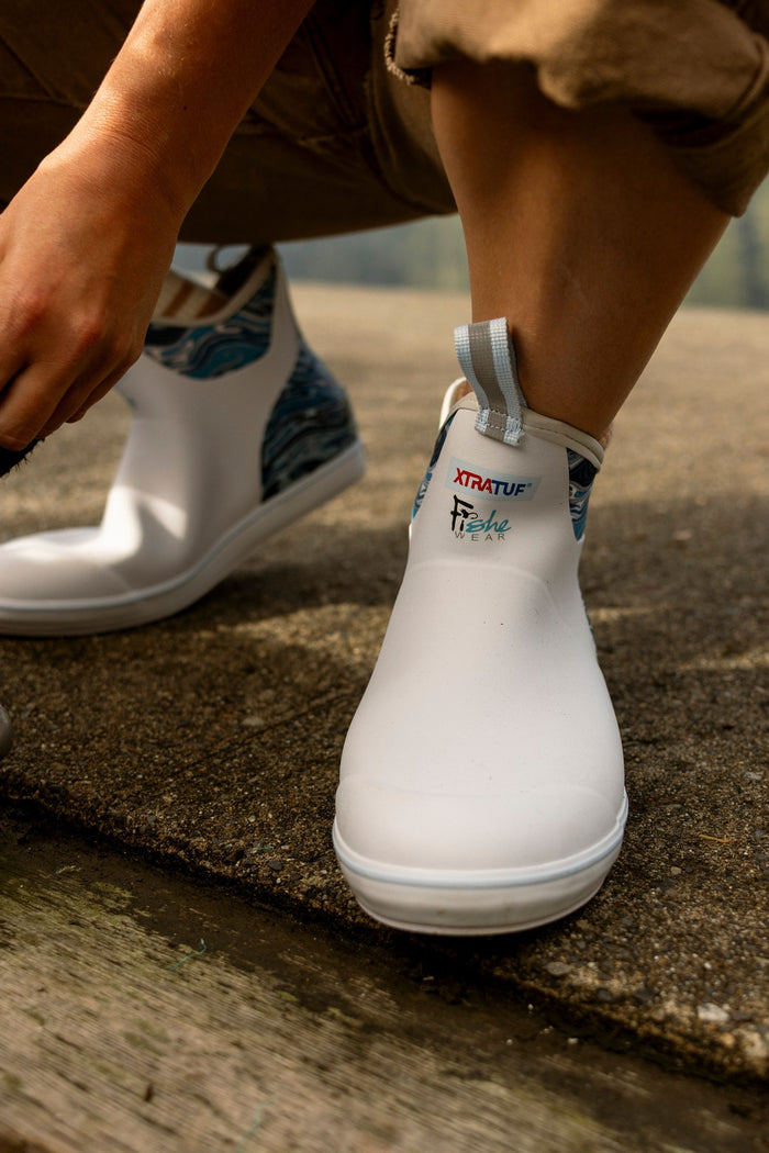 White rain boots with brand logo on a concrete surface