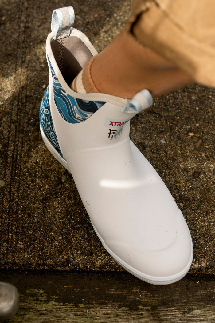 White slip-on shoe with blue patterned lining on a concrete surface