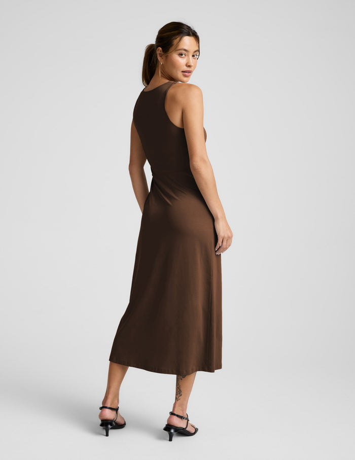 Woman wearing a brown square neck midi length dress against a plain background.