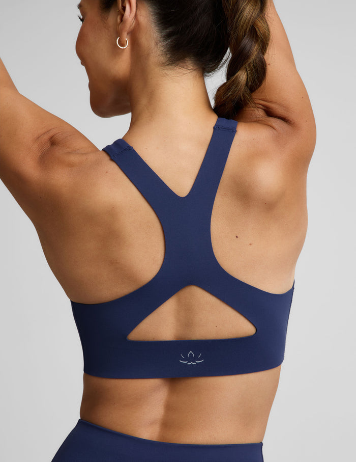 Woman wearing a blue sports bra and blue biker shorts against a plain background.