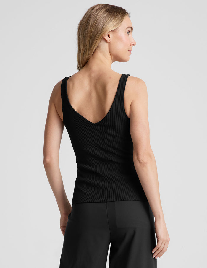 black ribbed tank top with a soft V neckline front and back​, overlapping front neckline detail, and a performance lining shelf bra. Tank hits at a high hip length.