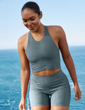 Woman wearing a blue ribbed cropped tank and shorts.