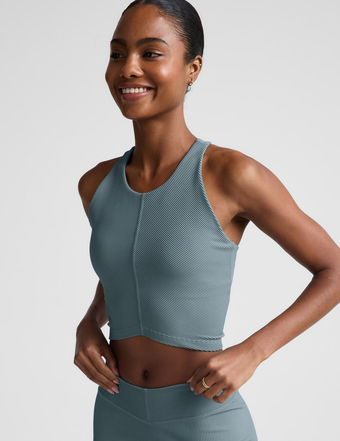 Woman wearing a blue ribbed cropped tank and shorts.