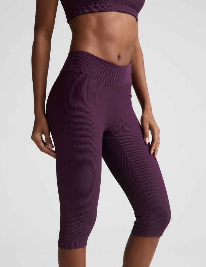 Woman wearing Plum Impulse™ Ribbed V-Waist Pedal Pusher Legging paired with a matching sports bra.