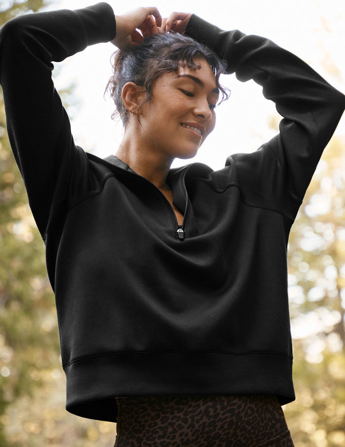 model wearing a black long length quarter zip pullover against a plain background.