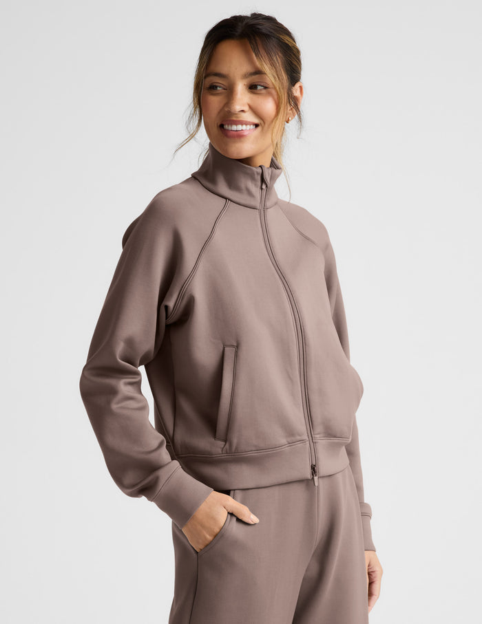 Woman wearing a brown tracksuit on a light gray background.
