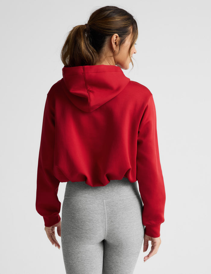 Woman wearing a red hoodie and gray leggings on a white background.