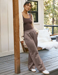Full-length beige In The Flow Wide Leg Pant with elastic waistband on a woman leaning against a wooden porch post.