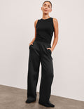 Woman wearing black In The Flow Wide Leg Pant with hands in pockets, featuring a high-waisted, loose, full-length fit.