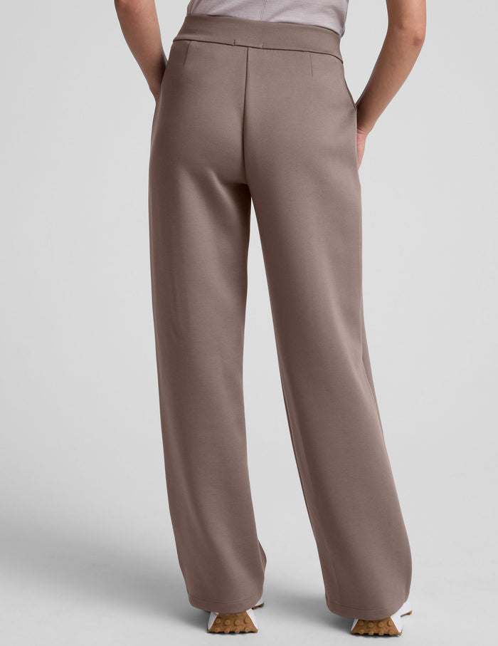Back view of a person wearing beige In The Flow Wide Leg Pants with a high waistband, welt pockets, and a loose, flowy fit.