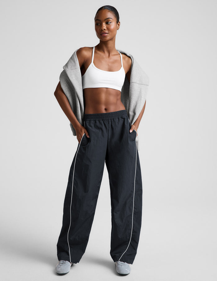 Front view of Limitless Mid-Rise Barrel Leg Pant in gray with white piping and a gathered elastic waistband on a model.