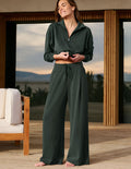 Woman wearing a green sweatshirt and green pants standing in front of a house.