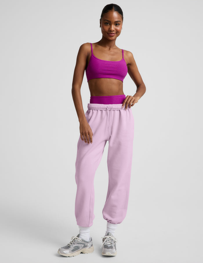 Woman wearing a purple bra and light purple fleece joggers against a plain background.