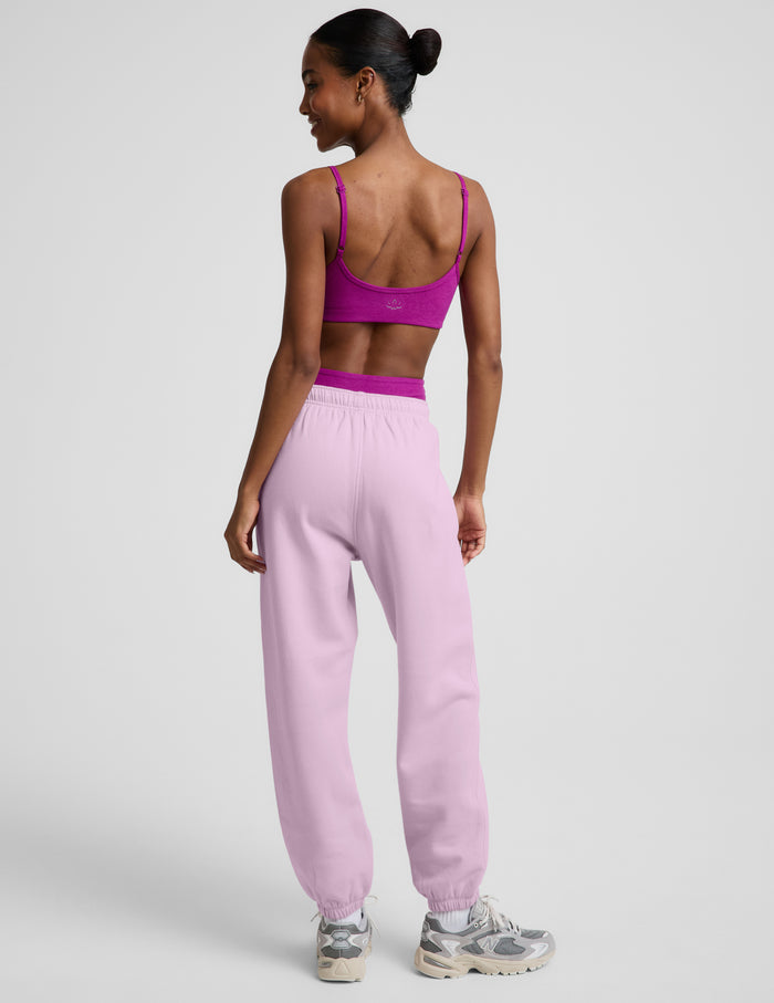 Woman wearing a purple bra and light purple fleece joggers against a plain background.