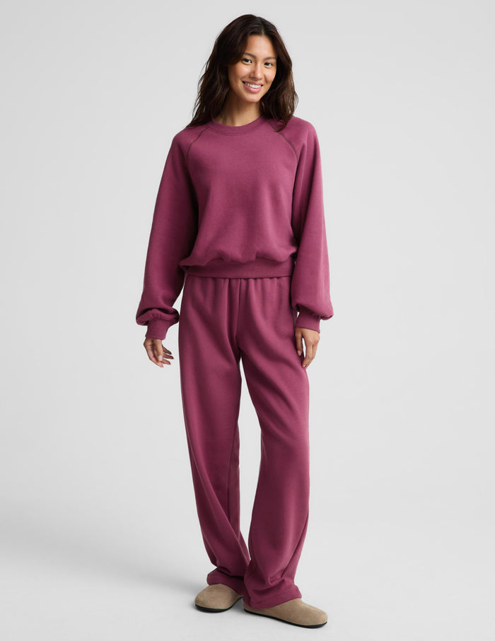 A woman modeling a matching dusty rose crewneck sweatshirt and jogger pants set against a light gray studio background.
