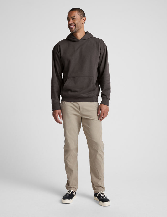 Man wearing a dark brown hoodie and beige pants on a white background | mens