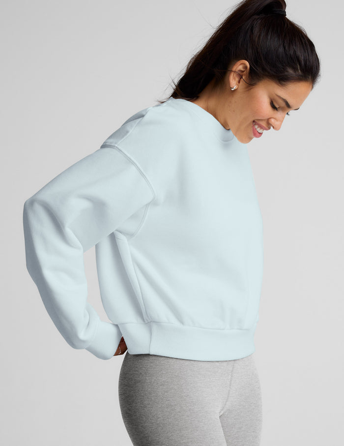 Woman wearing a light blue sweatshirt and gray leggings on a plain background.