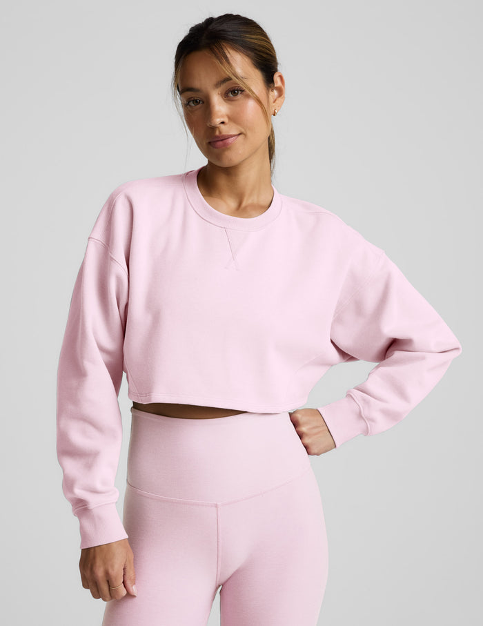 Woman wearing a pink sweatshirt and pants on a light gray background.