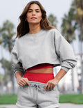 Woman wearing a gray sweatshirt and red top with gray shorts outdoors.