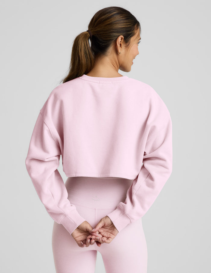 Woman wearing a pink sweatshirt and pants on a light gray background.