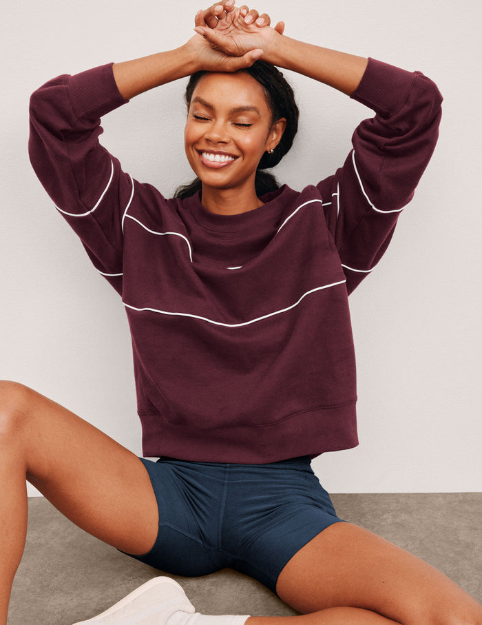 red fleece crewneck sweater with white contrast piping trim at chest and sleeves.