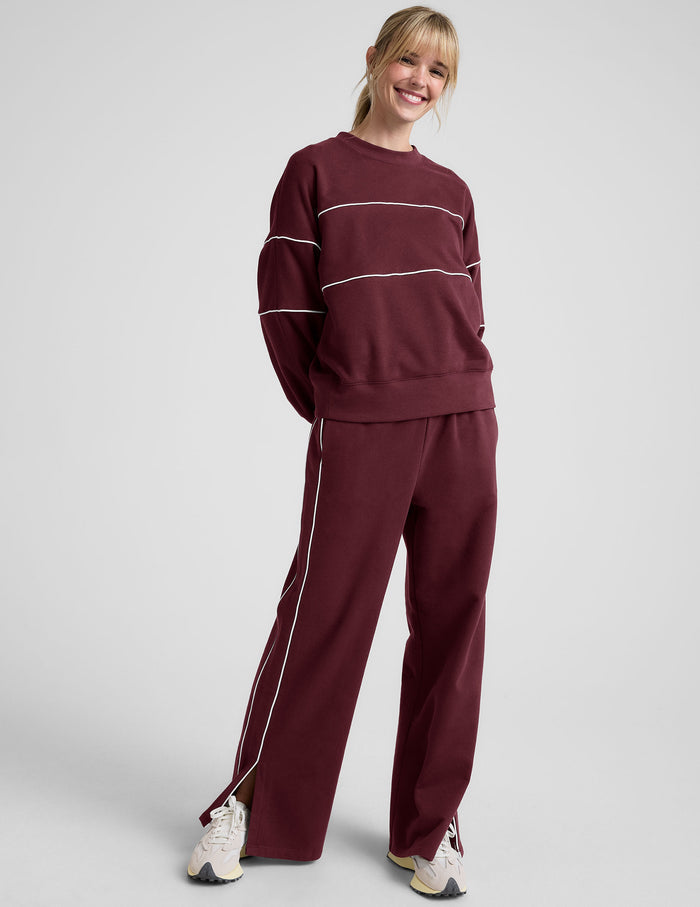 red fleece crewneck sweater with white contrast piping trim at chest and sleeves.
