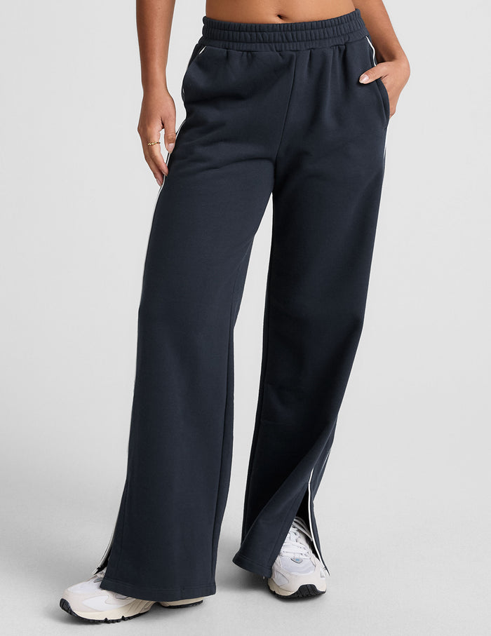 Navy LuxeFleece Piper Wide Leg Pant featuring white side piping, elastic waistband, slant pockets, and hem slits.