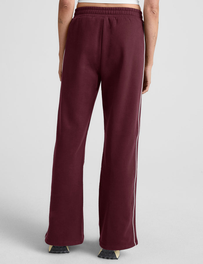 Back view of maroon LuxeFleece Piper Wide Leg Pant featuring white side piping and a comfortable elastic waistband.
