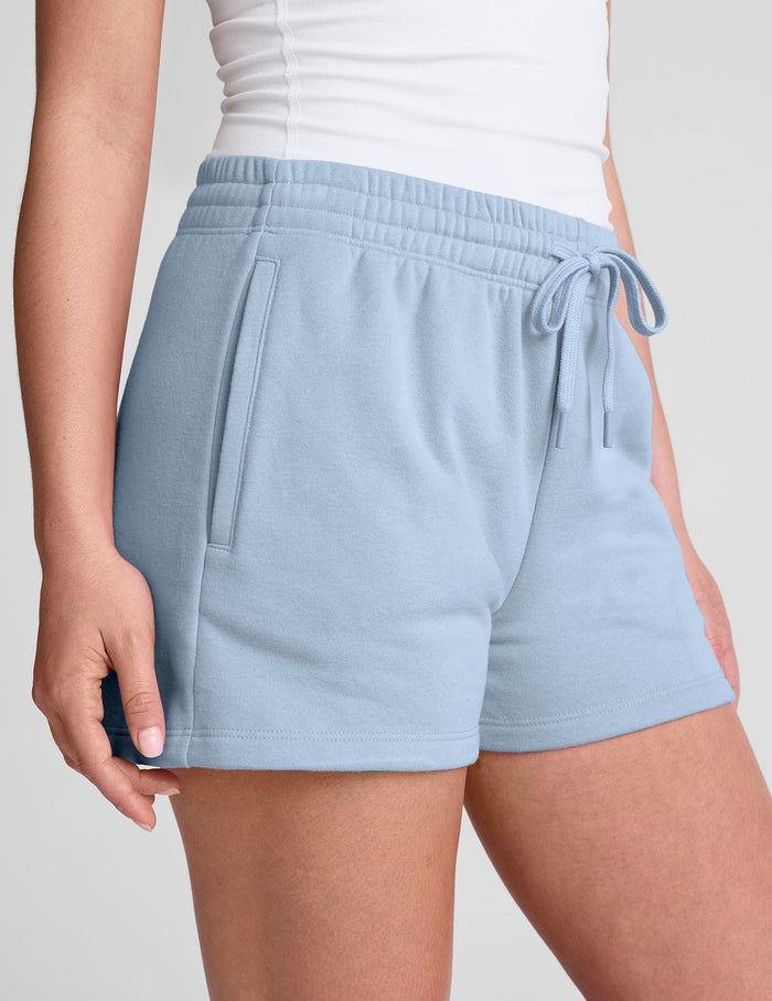 Light blue LuxeFleece Sweat Short with an elastic drawstring waistband and side pockets shown in a relaxed fit.