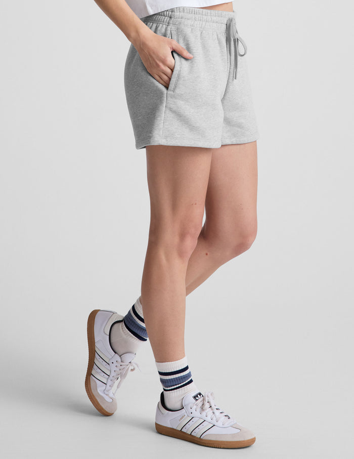 Side view of heathered gray LuxeFleece Sweat Shorts with a drawstring waistband and pockets on a model.