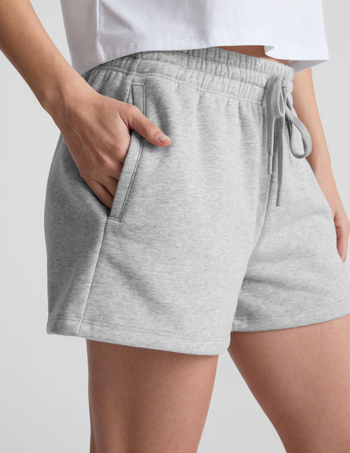 Light gray LuxeFleece Sweat Short featuring a marled texture, elastic drawstring waistband, and side pockets on a model.