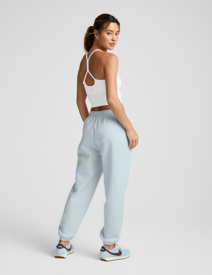 Woman wearing light blue LuxeFleece Sweatpant with relaxed fit, elastic waistband, and gathered cuffs, looking back.