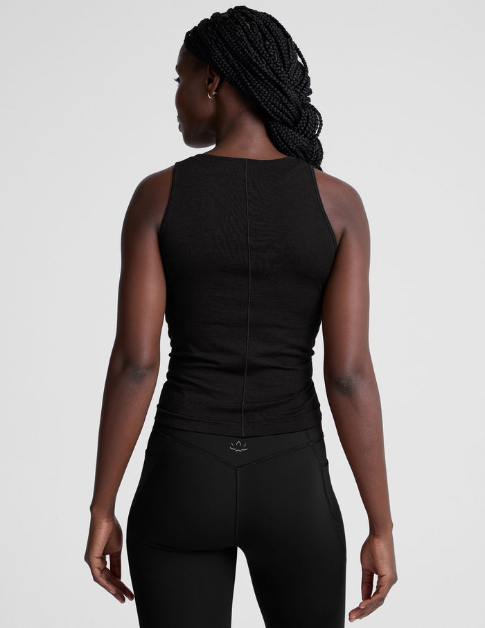 model wearing a scoop high neck racerback tank top against a plain background.
