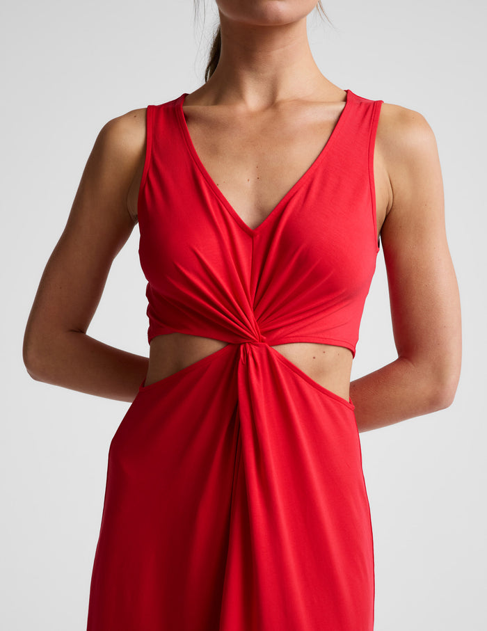 Woman wearing a red dress with cut-out design on a white background.