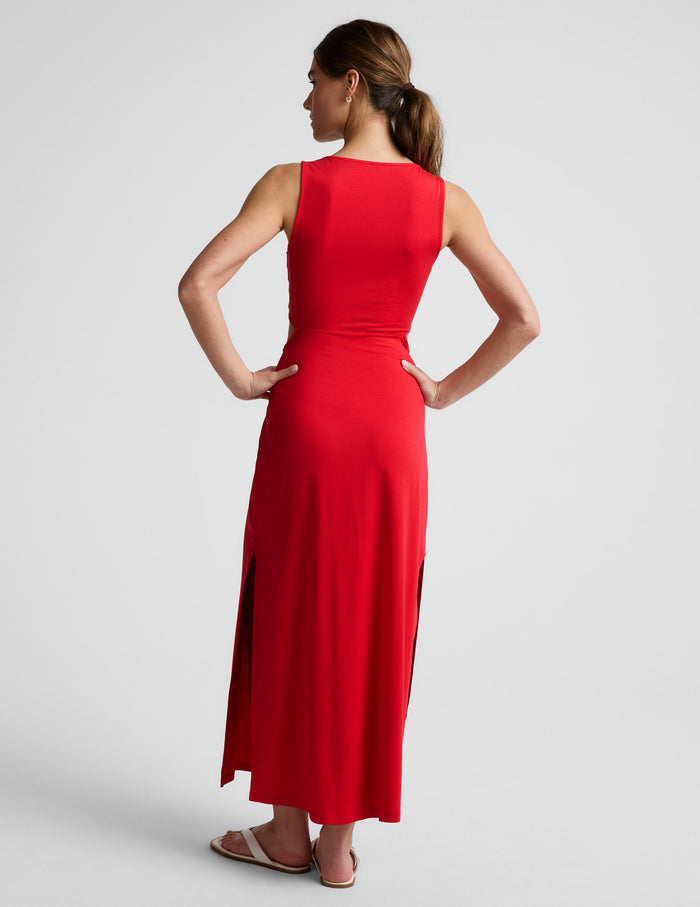 Woman wearing a red dress with cut-out design on a white background.