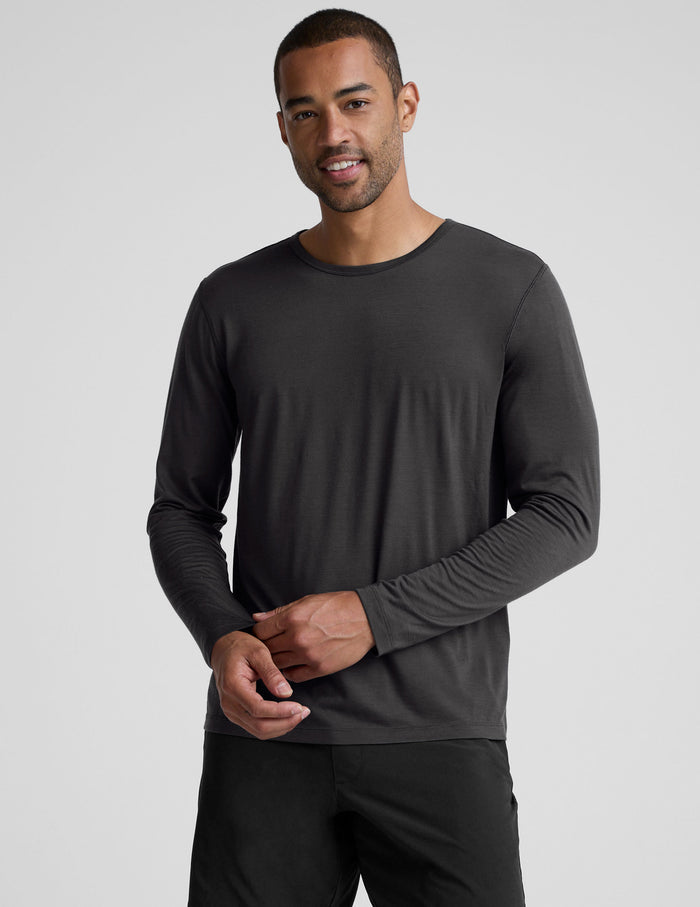 man wearing a black long-sleeve shirt against a plain background.