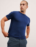 man wearing a blue crew neck t-shirt against a plain background.