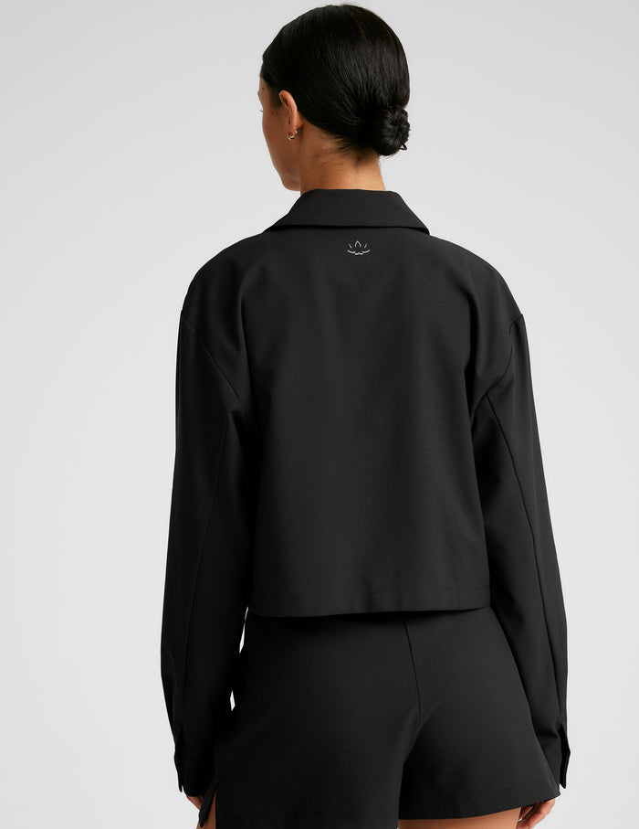 black cropped loose fitting jacket with a collar at neckline​, hidden placket with button closure at center front​, and front chest cargo pockets.