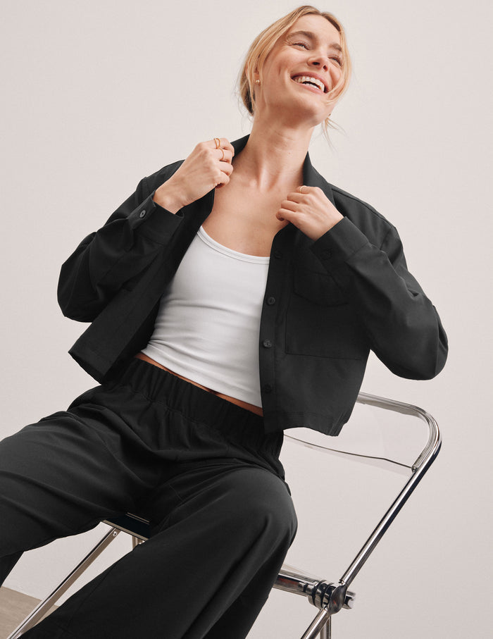 black cropped loose fitting jacket with a collar at neckline​, hidden placket with button closure at center front​, and front chest cargo pockets.