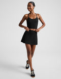 Woman wearing Black marled Midweight Spacedye Kickstart Skirt paired with a matching tank top and black sneakers.