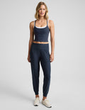 Woman wearing a blue tank top and blue joggers against a plain background.