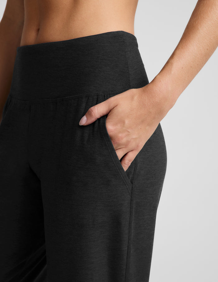 Woman wearing a black bra and black  joggers against a plain background.