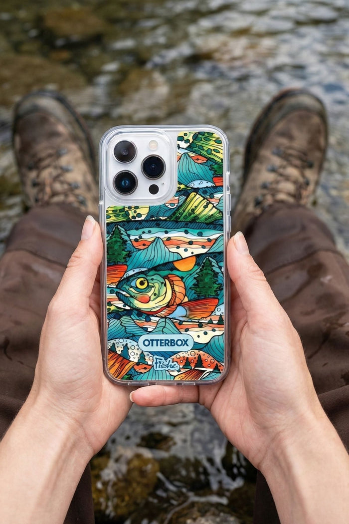 Person holding a phone with a colorful OtterBox case near a stream.