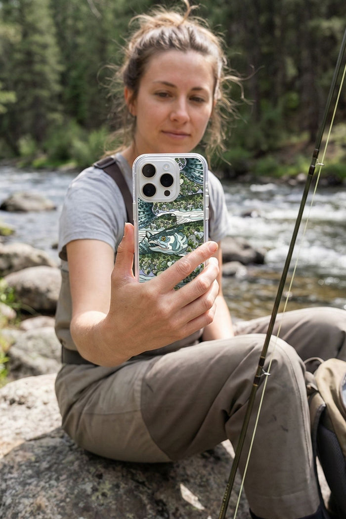 Person holding a phone with a nature-themed case by a river