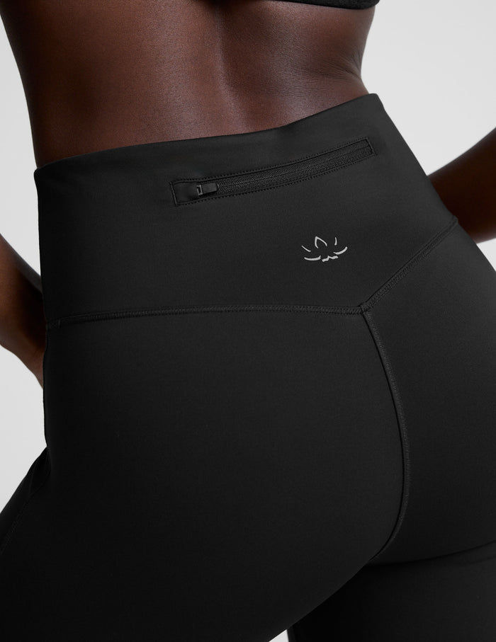 Rear view of the high-waisted black Pacer Fleece Pant, highlighting the back zipper pocket and small silver brand logo.