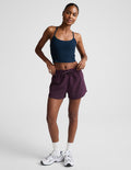 Woman wearing Purple Peak 3" Short™ with a navy tank top, featuring an elastic waistband and side patch cargo pockets.