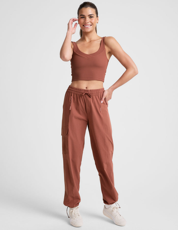 Woman wearing Brown Peak Pant™ with side patch cargo pockets, paired with a matching crop top and cream sneakers.